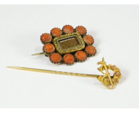 MOURNING BROOCH ETC. A 19th century carved coral mourning brooch with inset woven hair. Also, a gold horseshoe stick pin.  Pl