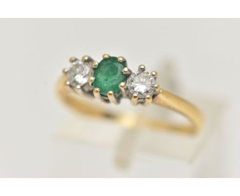 AN 18CT GOLD EMERALD AND DIAMOND RING, the central oval emerald flanked by brilliant cut diamonds, all within claw settings, 