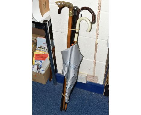 A GROUP OF FOUR WALKING STICKS AND A VINTAGE UMBRELLA, comprising a grey floral umbrella, a silver topped ebonized walking ca