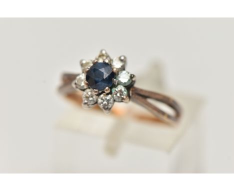 AN 18CT SAPPHIRE AND DIAMOND CLUSTER RING, the central circular sapphire within a brilliant cut diamond surround, to the bifu