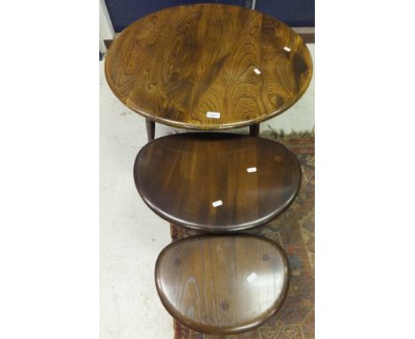 An Ercol circular mid elm coffee table, together with two Erco mid elm pebble shaped tables on three legs, a white painted ru