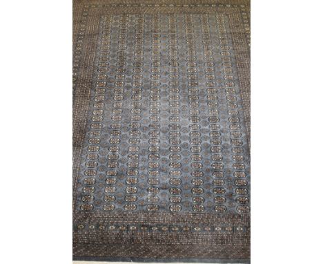 A Bokhara carpet, the repeating elephant foot medallions in salmon, blue/grey and cream, on a blue/grey ground, within simila