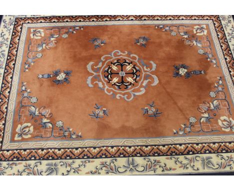 A Chinese carpet, the central blue and cream medallion on a salmon ground, within cream, blue and salmon scrolling foliate de
