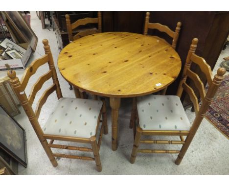 A modern circular pine table, raised on four turned legs and four pine ladder back chairs