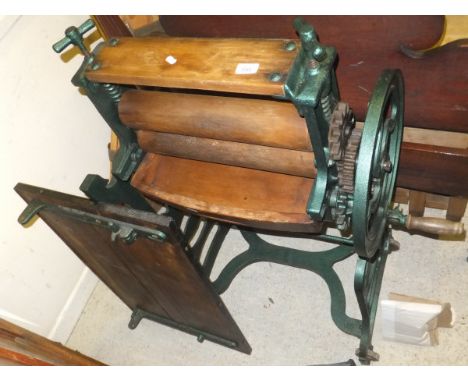 A painted cast iron mangle inscribed "Gordon" and "Timothy Whites of Taylors Ltd" with enamel covered table top 