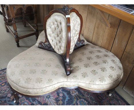 A Victorian three seat conversation sofa with a carved walnut frame, the top surmounted by three carved flowers, with pale go