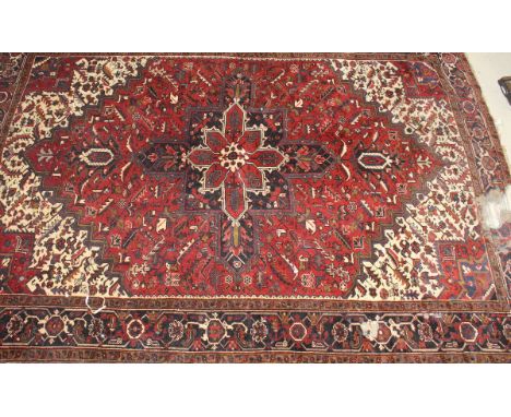 A Caucasian carpet, the central medallion in burgundy, cream and dark blue, on a burgundy stylised foliate decorated ground, 