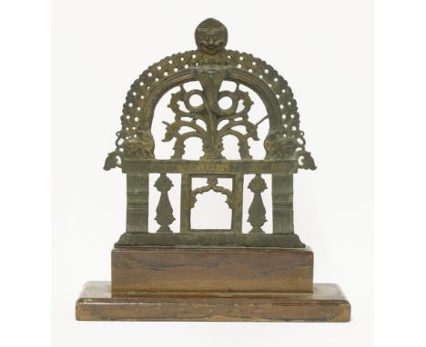 An Indian bronze shrine,possibly 18th century, with a pierced flame aureole surmounted by a mask finial, mounted on a later w
