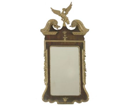 A gilt and walnut wall mirror,18th century and later, with a gilt eagle finial, with a scrolled arch pediment moulded edge wi