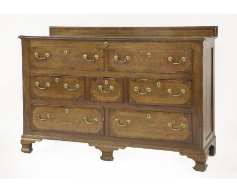 A George III oak and mahogany Lancashire chest,the hinged top over an arrangement of drawers, raised on ogee bracket feet, 15