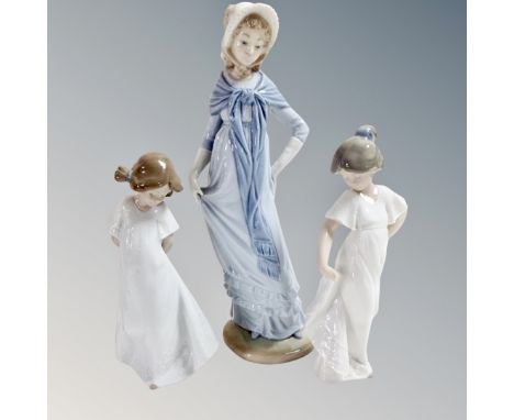 A Nao figure of a lady in Victorian dress, together with two further Nao figures of children in white dress. 