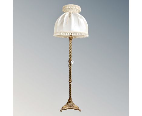 An ornate brass barley twist column standard lamp on paw feet with silk shade 