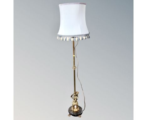 A brass figural cherub standard lamp on circular brass base and paw feet with silk tasseled shade 