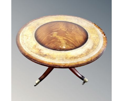 A circular mahogany coffee table on four-way pedestal with leather inset panel 
