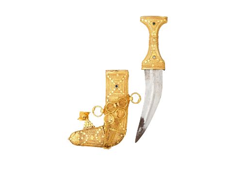 ‡ AN ARAB GOLD-MOUNTED DAGGER (JAMBIYA), 20TH CENTURY with curved double-edged blade formed with a medial ridge, gilt hilt de