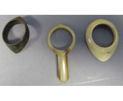 ˜THREE EASTERN ARCHERS' RINGS the first perhaps Seljuk, of brass, engraved with patterns of concentric circles,with pronounce