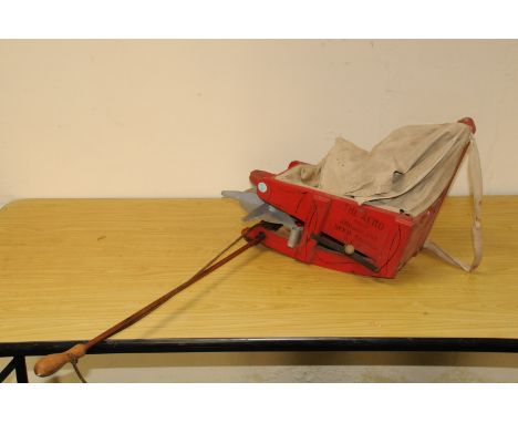 A shoulder mounted seed fiddle / dispenser, named The Aero, with red wooden painted body and cloth hopper 