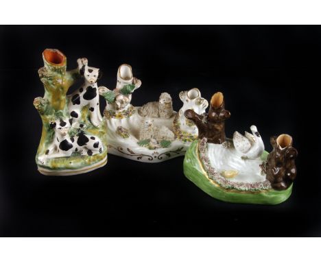 Three 19th century Staffordshire mantle bud vases, each modelled as animal groups, including sheep, spaniels, and swan with a