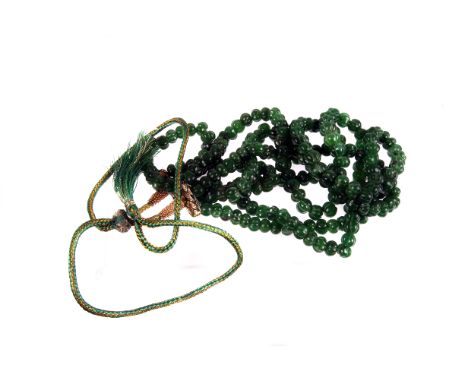 An emerald bead three strand necklace,  composed of graduated melon cut beads, to a silk cord tie 