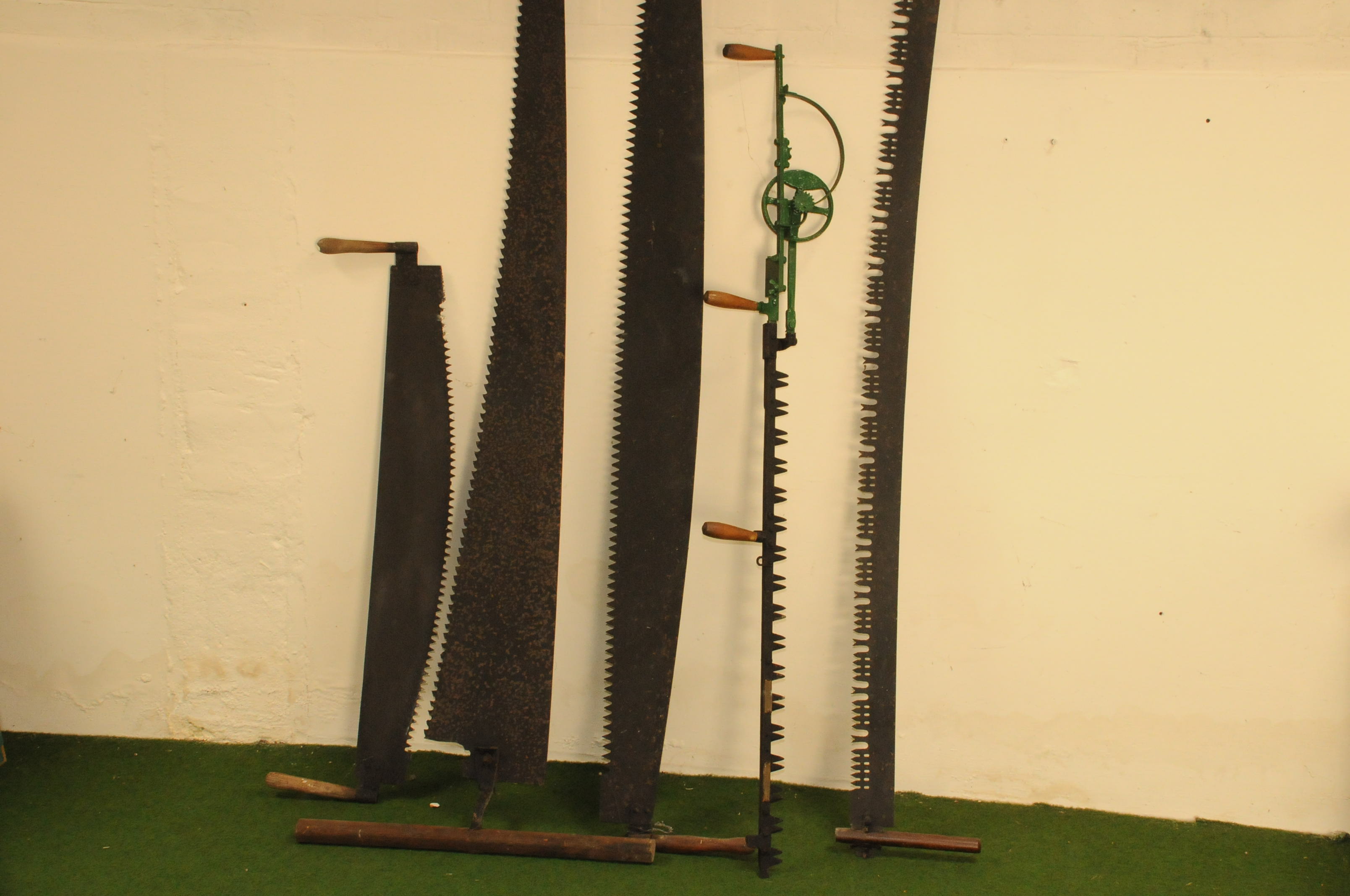 A group of four antique wood cutting saws and a hedge trimmer, the hand
