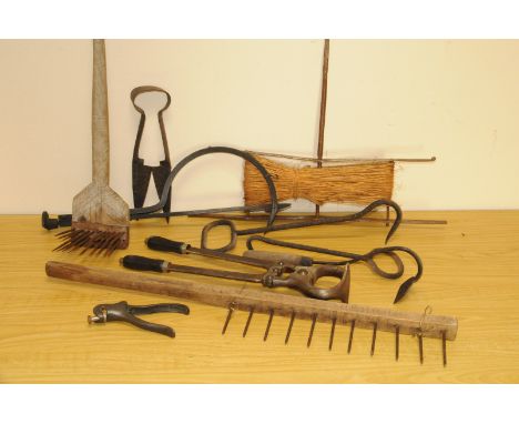 A collection of antique and vintage farm hand tools, including a thatcher's hook, a wooden yoke, a thatcher's comb, several h