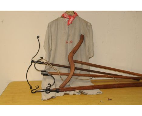 A group of antique and vintage shepherding tools and items, including various wooden and metal crooks, a cotton smock embroid