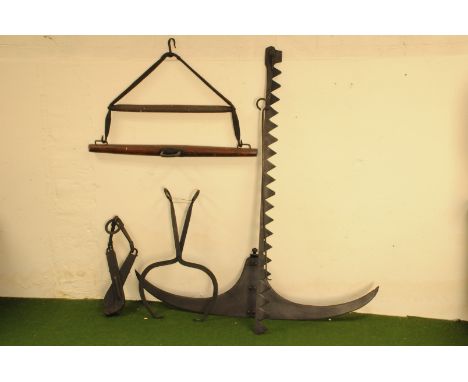 A group of five vintage farm tools and utensils, including a large twin bladed reed cutter, one part of a saw bladed grass cu