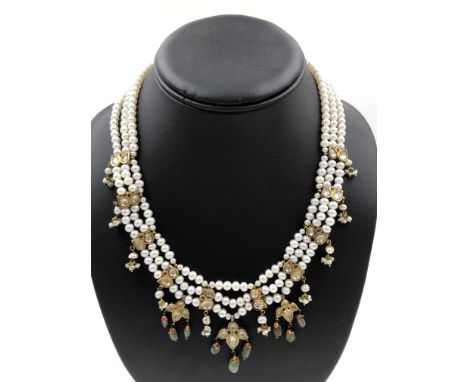 A TRADITIONAL TRIPLE ROW PEARL AND GEMSET NECKLACE. THE PEARLS STRUNG TO MEET GEMSET KUNDAN SPACERS WITH ACCENTS OF CABOCHON 