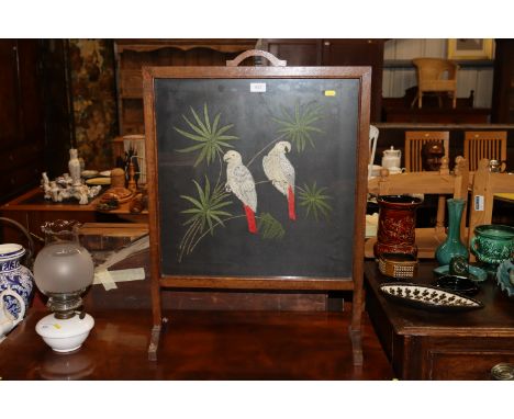 An oak framed fire screen the embroidered panel depicting parrots and branches 