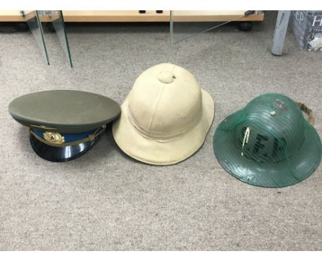 A collection of military hats consisting of a USSR Aviation cap, a WW2 Pith helmet marked 1943 and a steel helmet. Postage ca