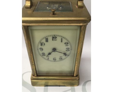 A brass case carriage clock the dial with Arabic numerals having a button and repeat movement.