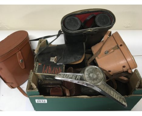 A collection of Vintage camera equipment and a chrome tractor plate Ford Major.