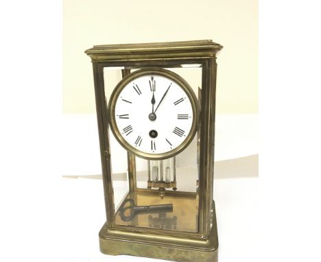 A brass four glass mantel clock with a mercury pendulum and white enamel dial. With key.