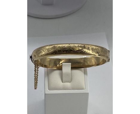 A 9ct yellow gold bangle, 13.6 grams approx, safety chain, in good condition, 10mm wide x 7 1/2 inches round