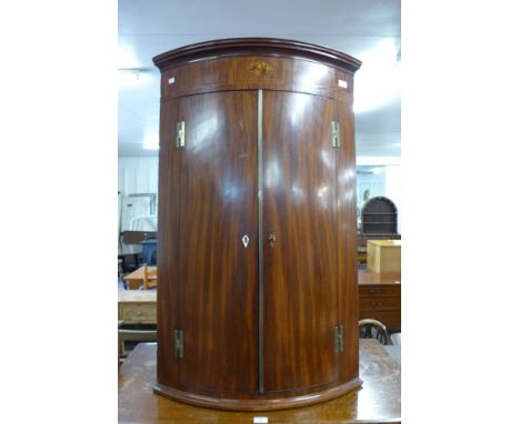 A George III inlaid mahogany bow front hanging corner cupboard