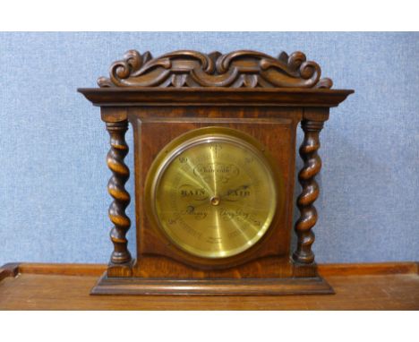 A carved oak aneroid barometer, A.W. Gamage Ltd., London, glass a/f