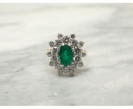 An Emerald and Diamond Cluster Ring claw-set oval-cut emerald within double frame of brilliant-cut diamonds in 18ct gold, rin