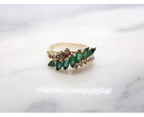 An Emerald and Diamond Ring the crossover-mount set seven marquise-cut emeralds between rows of brilliant-cut diamonds, stamp