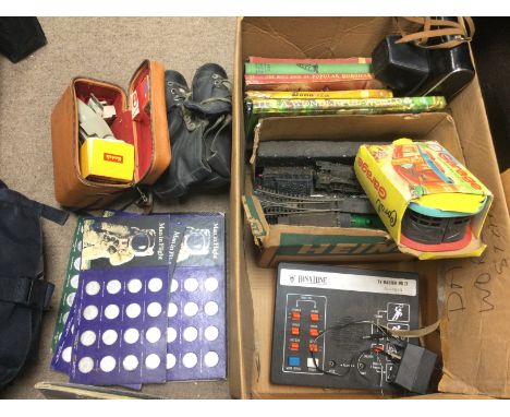 A box of oddments comprising a vintage pair of skates, a Binatone TV Master MKIV, coin sets etc. Shipping category D.