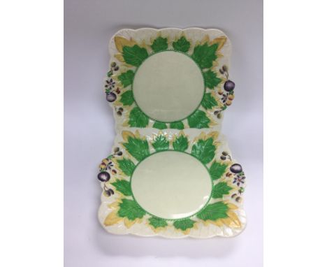 A pair of Clarice Cliff dishes decorated with leaves and fruit on an ivory ground, approx diameter 27cm.