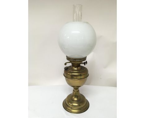 A brass oil lamp with opaque glass shade and glass chimney.