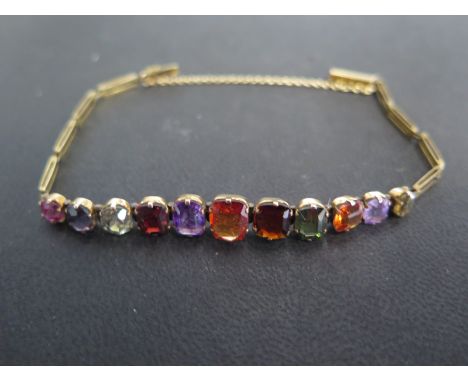 A tested as 9ct yellow gold and multi gem bracelet set with eleven graduated rectangular cut stones - light usage wear 