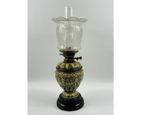 A late 19th century Doulton Lambeth oil lamp with a glass chimney and etched glass shade, decorated in typical style, impress