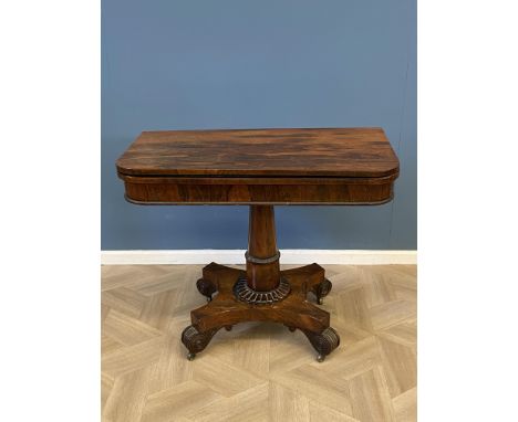An early Victorian rosewood fold over top card table with an inset baize playing surface, tapered cylindrical and beaded cent