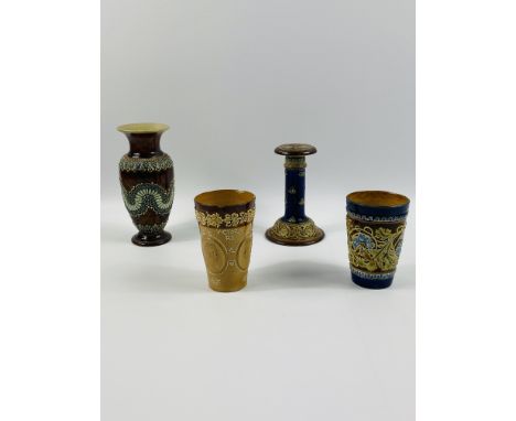 Four Doulton Lambeth items to include: a candlestick; two beakers and a vase, 20cms, all with impressed marks to the base. Es