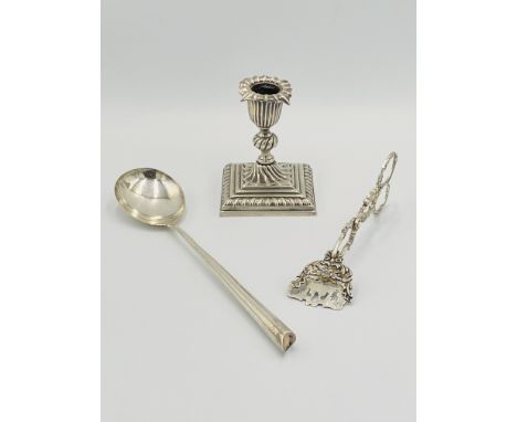 A silver candlestick with weighted base, 1887; a silver salad server, 52g, London 1896; a pair of white metal tongs. Estimate