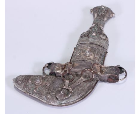 A Middle Eastern silver mounted jambiya dagger, 9cm curved blade with central ridge, the hilt and scabbard profusely applied 