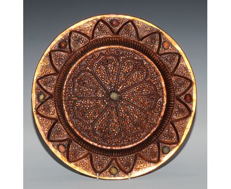 A Tibetan copper circular charger, chased with stylised lotus and set with jade and agate cabochons, 37cm diam 