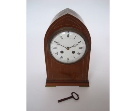 An early 20th Century mahogany arched mantel clock, with 12cm diameter circular white enamel dial, Roman numerals and minute 