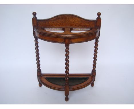 An early 20th Century oak demi lune stick/umbrella stand, with barley twist upright supports and metal drip tray. 